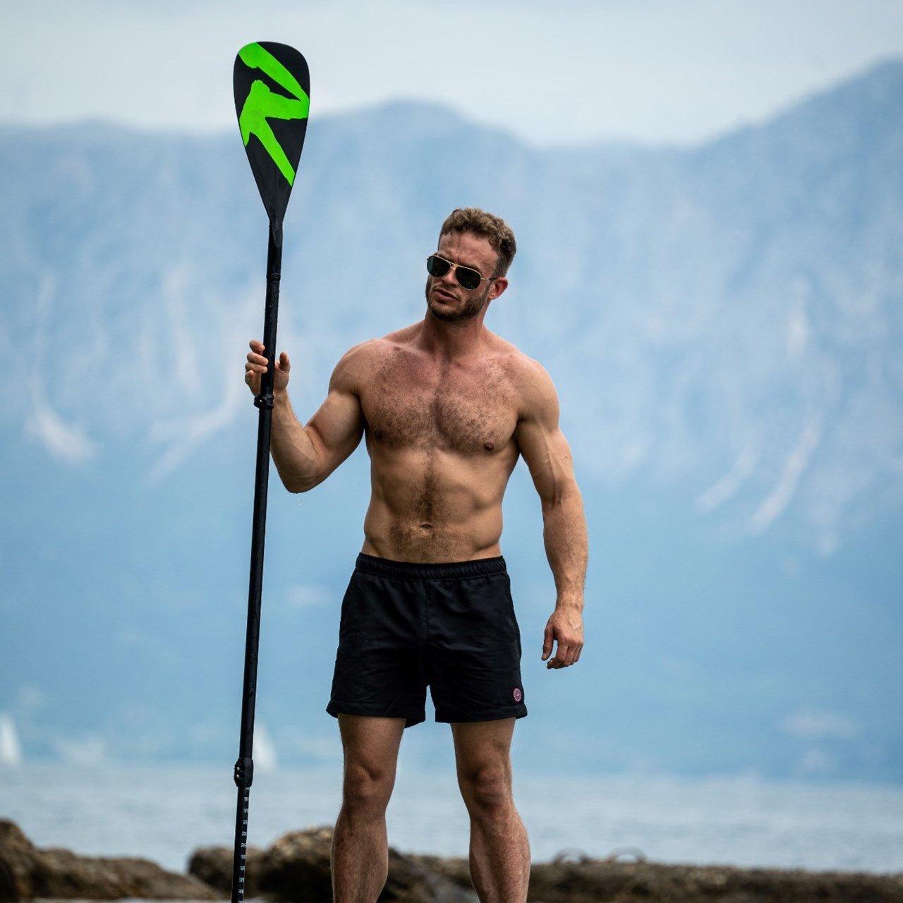 man standing on top of his paddleboard holding a sup paddle